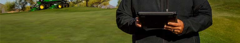 Superintendent holding an ipad in front of their golf course.